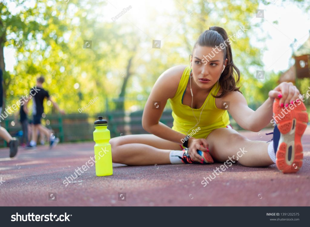 stock-photo-front-view-of-beautiful-young-woman-in-sportswear-doing-stretching-while-sitting-on-ground-1391202575