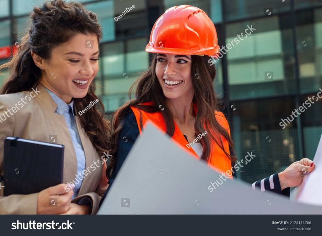 stock-photo-engineers-examining-plans-on-construction-site-to-client-business-woman-looking-at-a-plan-2128111706
